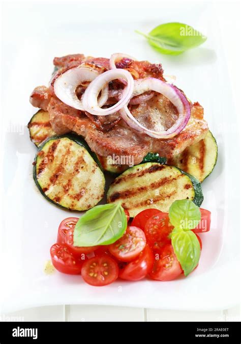 Pan Fried Pork Steak With Grilled Vegetable And Tomato Salad Stock