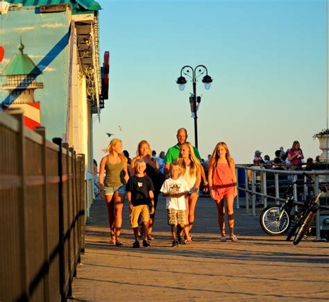 A Group Of People Walking Down A Pier