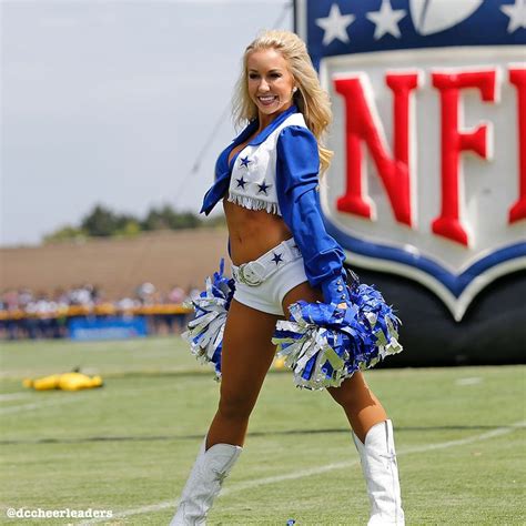 A Cheerleader Is Posing For The Camera In Front Of A Nfl Sign And Field