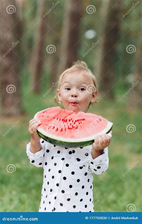Cute Little Girl Eating Big Piece Of Watermelon On The Grass In