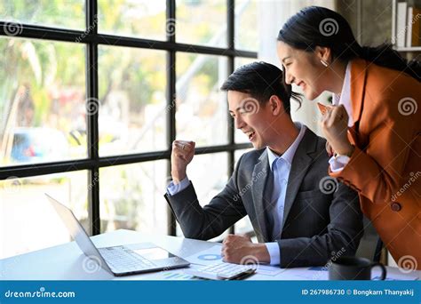 Two Happy Asian Businesspeople Showing Clenched Fist Looking At Laptop Screen Celebrating