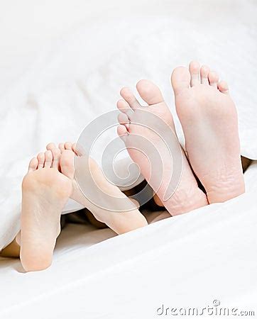 Close Up Of Feet Of The Couple Lying In Bed Royalty Free Stock Photos