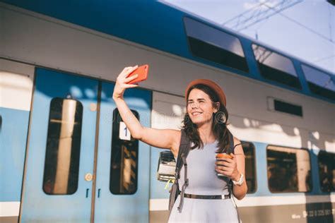 cheerful woman traveler with backpack taking photo selfie in train station travel lifestyle