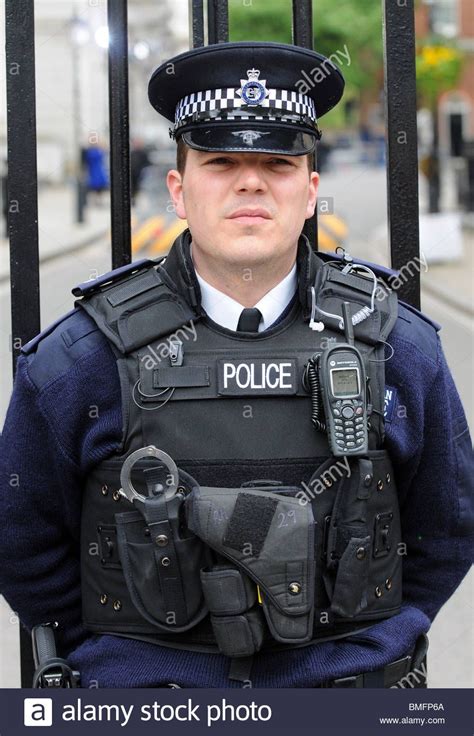 A Police Officer Standing In Front Of A Gate With His Cell Phone On His