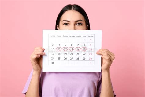 Young Woman Holding Calendar With Marked Menstrual Cycle Days On