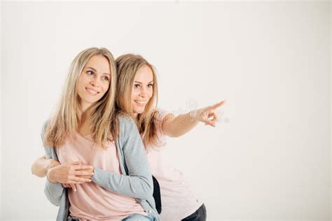 Dos Gemelos Attrative De Las Hermanas Que Señalan Sobre El Fondo Blanco