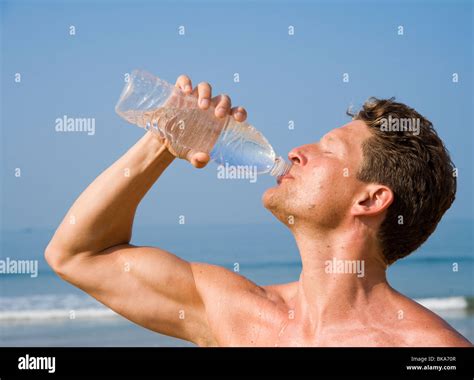 A Man Drinking Bottled Water On A Beach Stock Photo Alamy
