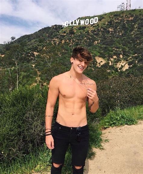 A Shirtless Man Standing In Front Of The Hollywood Sign With His Hand On His Hip