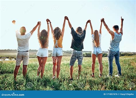 Group Of Happy Young People Holding Hands Raised Together On The Sky