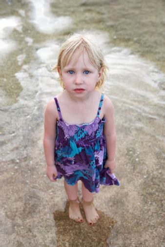 Beautiful Little Girl Standing On Seawater Looking Up Stock Photo