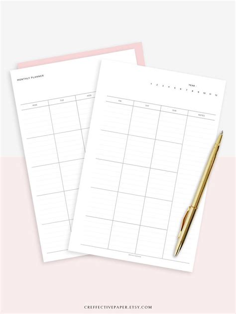 Two Blank Calendars On Top Of Each Other With A Gold Pen Next To Them