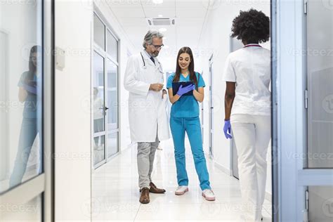 Female Surgeon And Doctor Walk Through Hospital Hallway They Consult