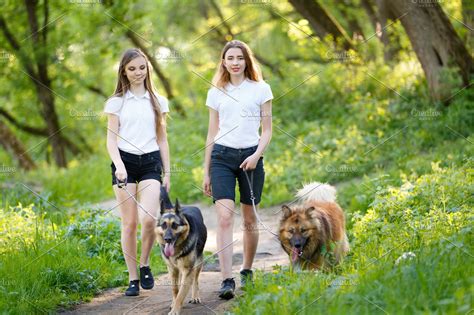 Two Teenage Girls Walking With Her Dogs In Park High Quality People