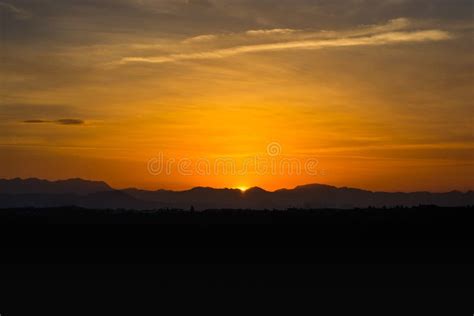 Golden Sky And Sun Hiding Behind The Mountain Silhouette In The Time Of