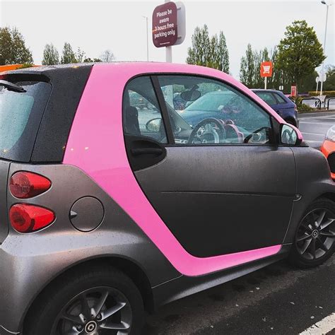 A Smart Car With Pink Trim Parked In A Parking Lot