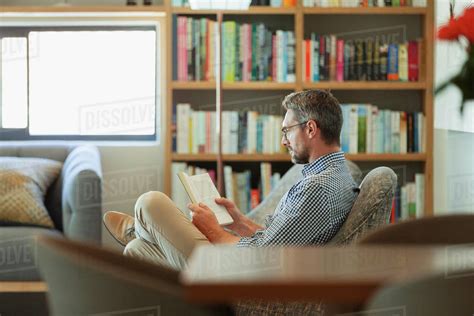 Man Relaxing Reading Book In Living Room Stock Photo Dissolve