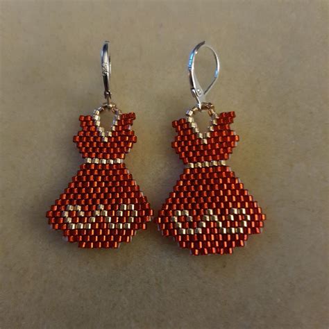 Two Pairs Of Red And Silver Beaded Earrings On A White Surface With One