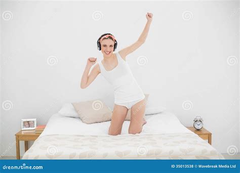 Young Woman Kneeling On Her Bed And Listening To Music Royalty Free