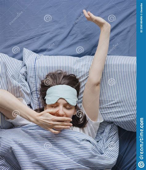 Top View Of A Woman In Bed Wearing A Sleep Mask A Happy European Woman Wakes Up And Stretches