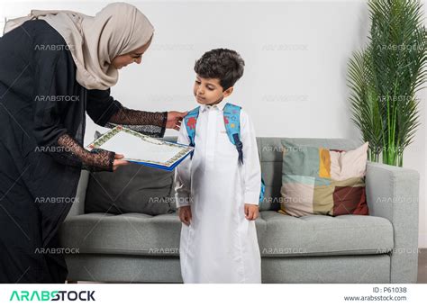 طفل عربي خليجي سعودي يرتدي حقيبة الظهر المدرسية، ارتداء الزي المدرسي، أم تعطي طفلها الكتب