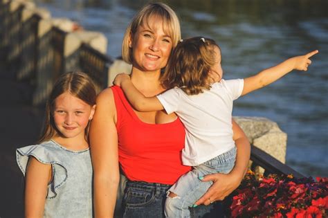premium photo beautiful blonde mom in a red t shirt with her daughters on the embankment