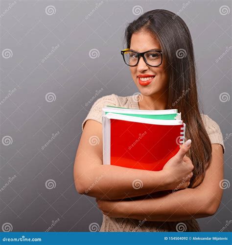 Portrait Of Happy Student Woman Holding Books With Thumb Up Against