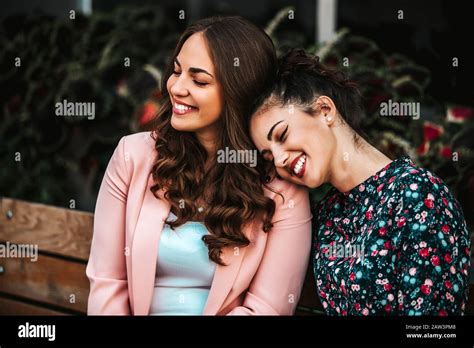 Happy Best Female Friends Enjoying Together Sitting In A Bench