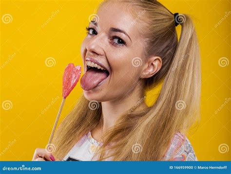 Schönes Blondes Mädchen Hält Ihre Zunge Heraus Um Einen Rosa Lollipop Zu Schmecken Stockfoto