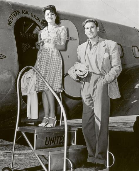 A Man And Woman Standing In Front Of An Airplane