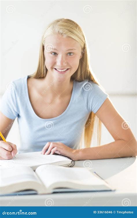 Happy Teenage Student Sitting At Desk In Classroom Stock Photo Image