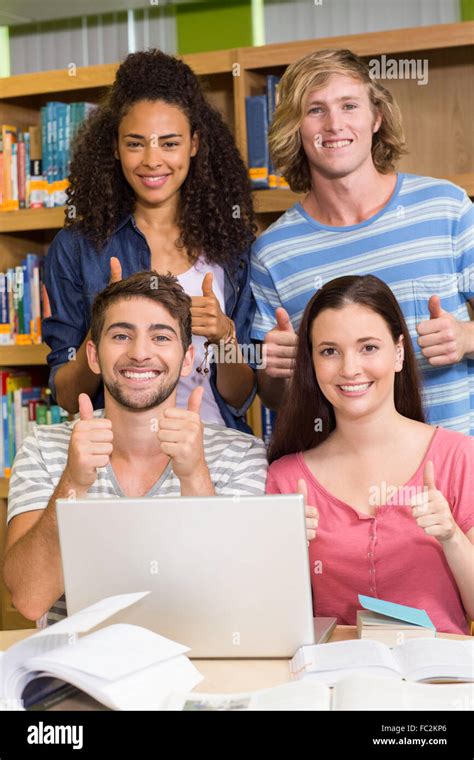 College Students Gesturing Thumbs Up In Library Stock Photo Alamy