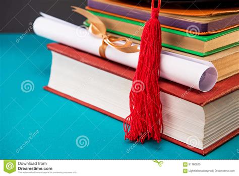 Close Up Of Books Diploma And Graduation Cap With Tassel On Blue Stock