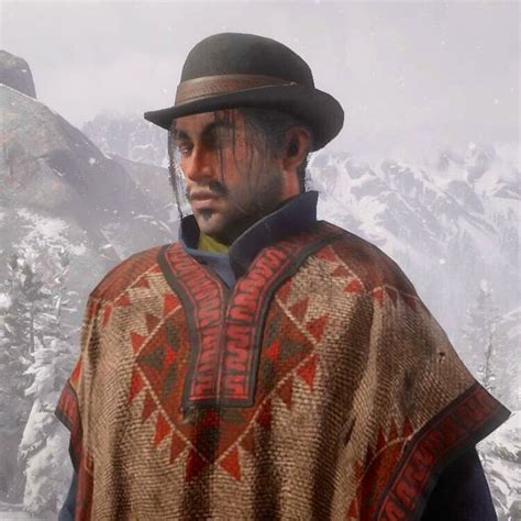 A Man With A Hat And Cape On Standing In Front Of Snow Covered Mountain