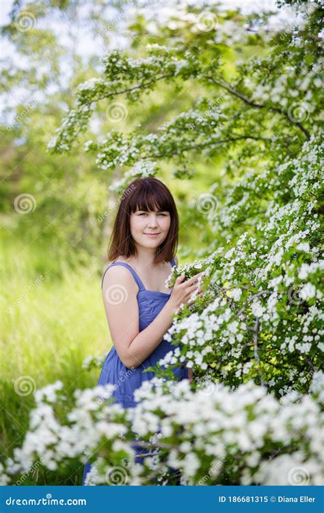 Portrait Of Beautiful Woman Posing With Blooming Tree In Summer Garden