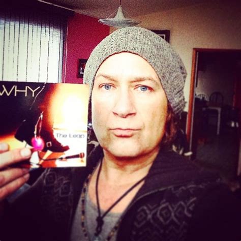 A Man In A Beanie Holding Up A Vinyl Album With The Word Why On It