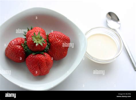 Fresh Strawberries And Cream Served In A White Dish And Shot On A White
