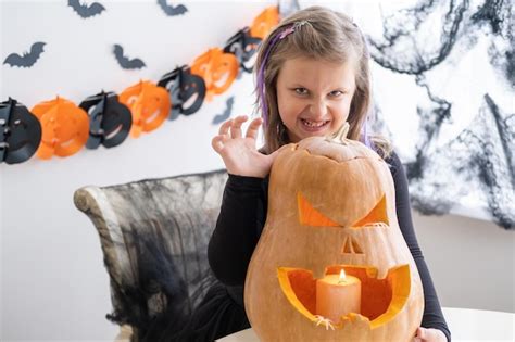 Premium Photo Cute Girl In Costume Of Witch With Pumpkin At Home Having Fun Celebrating