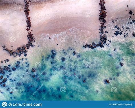 Aerial View Of Sandy Beach With Waves Clear Ocean Water And Big Black