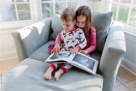 Little Brother Looking At A Photo Album With His Big Sister By Stocksy Contributor Jakob