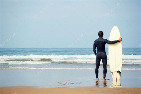 Atractivo Joven Surfista Sosteniendo Tabla De Surf Mientras Está De Pie