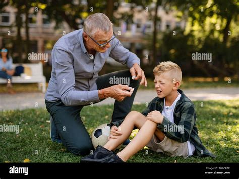 Little Boy With Injured Leg Crying His Grandfather Is Giving Him