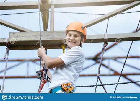 Active Sporty Kid In Helmet Doing Activity In Adventure Park With All Climbing Equipment Active