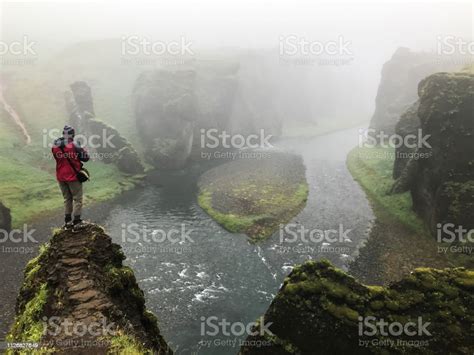 Man Standind On Cliff Overgrown With Green Moss Surrounded By A Very