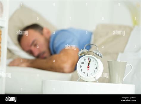 Alarm Clock Waking Sleeping Man In Bed Stock Photo Alamy