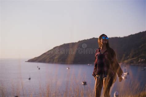 Hipster Stylish Woman Traveler Looking On A Sea Or Ocean At The Sunset