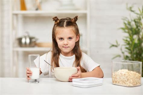 Little Girl Eating Breakfast Cereal With The Milk In The Kitchen