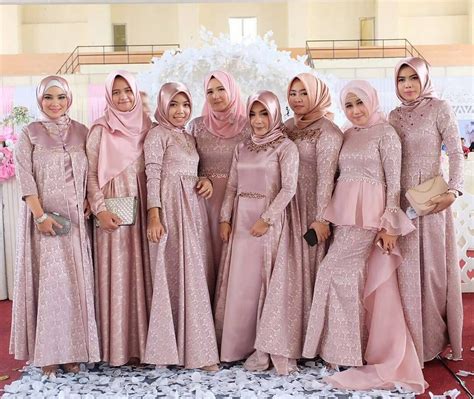 A Group Of Women Standing Next To Each Other Wearing Pink Dresses And Hijabs
