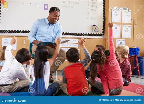 Elementary School Kids Sitting Around Teacher In A Classroom Stock