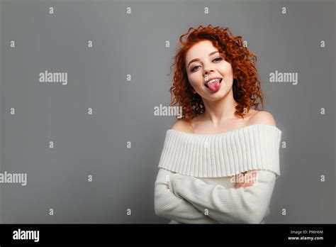 A Young Curly Haired Red Haired Girl Jokingly Shows Her Tongue In The Camera With Her Hands