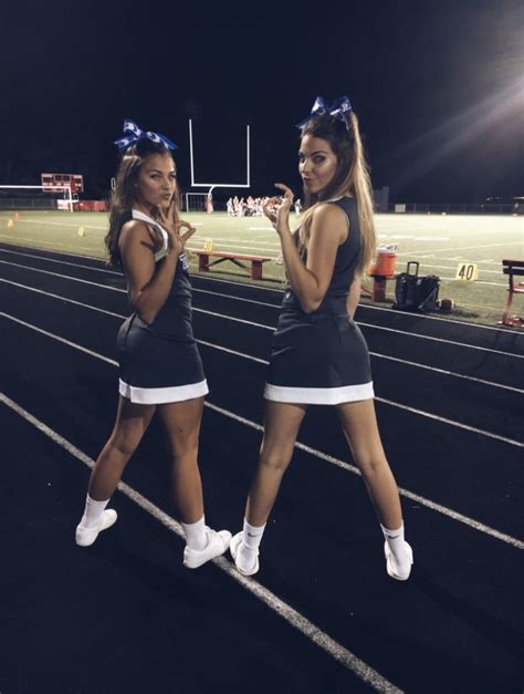 two cheerleaders are standing on the track